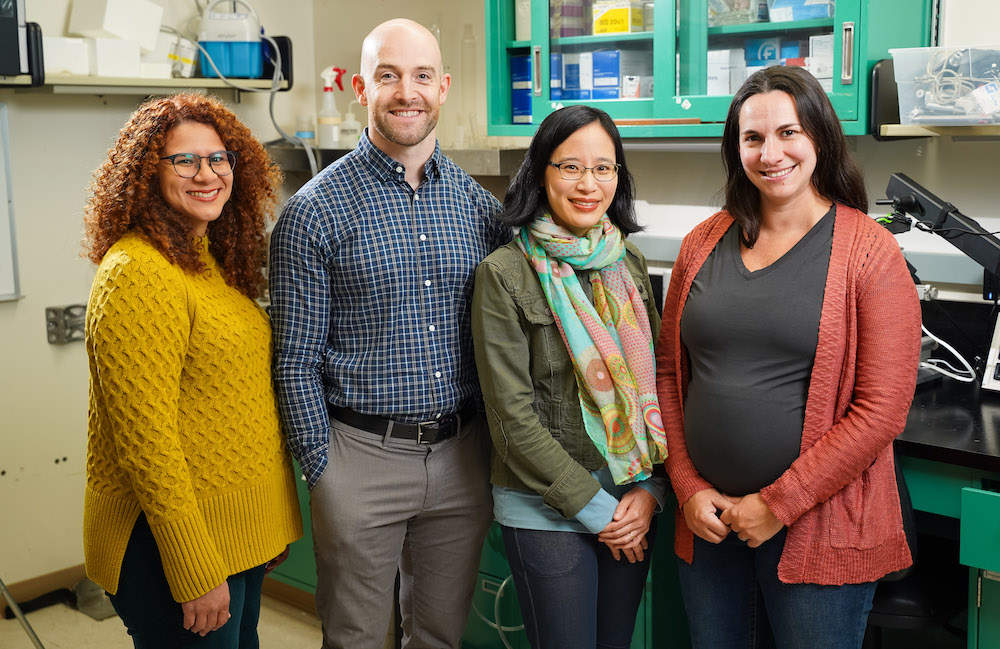 SHARP researchers smiling in front of lab equipment